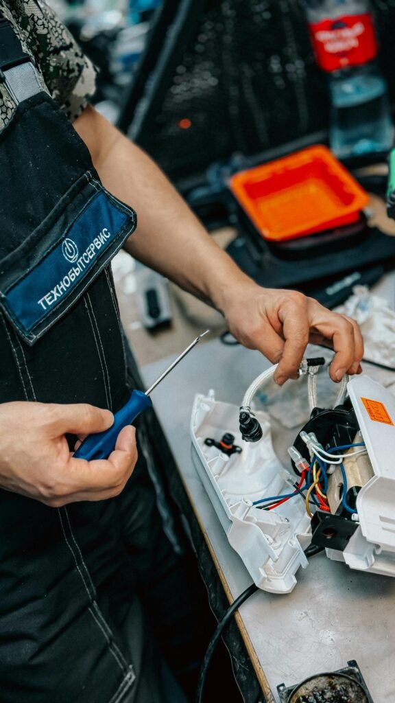 Close-up of a technician using a screwdriver to repair an electrical device in a workshop setting.